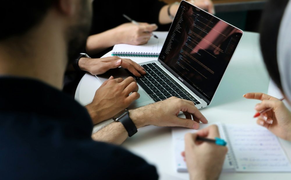 Grupo de personas revisando gráficos de mercado en un portátil durante una reunión